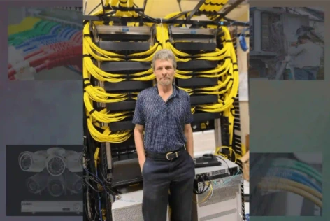 Cable Guy technician standing in front of network equipment